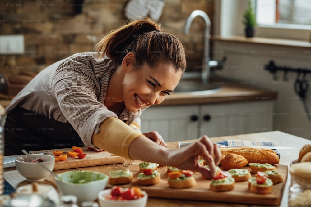 Young happy woman enjoying while making bruschetta in the kitchen.