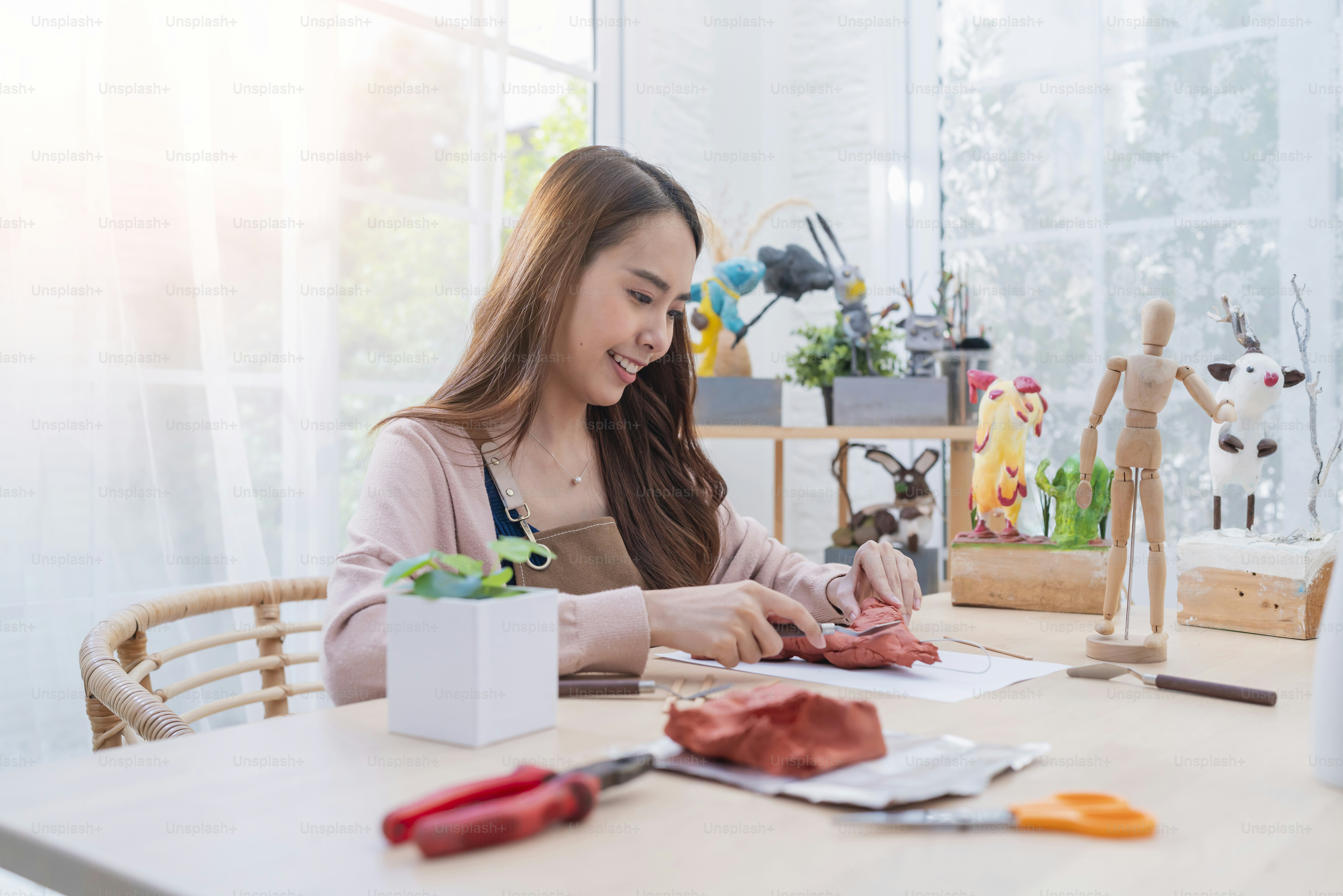 Asian Female artist an arttoys clay sculpture spend weekend day for her hobby clay scuplt properly define the form face anatomy, while making the clay statue at home studio casual lifestyle at home