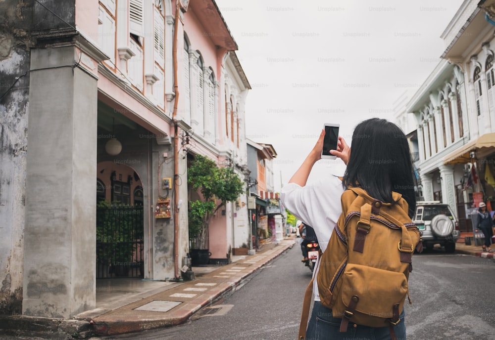 여행자 배낭 여행자는 여행하는 동안 구시 가지 도시의 사진을 찍는 휴대 전화를 사용합니다.