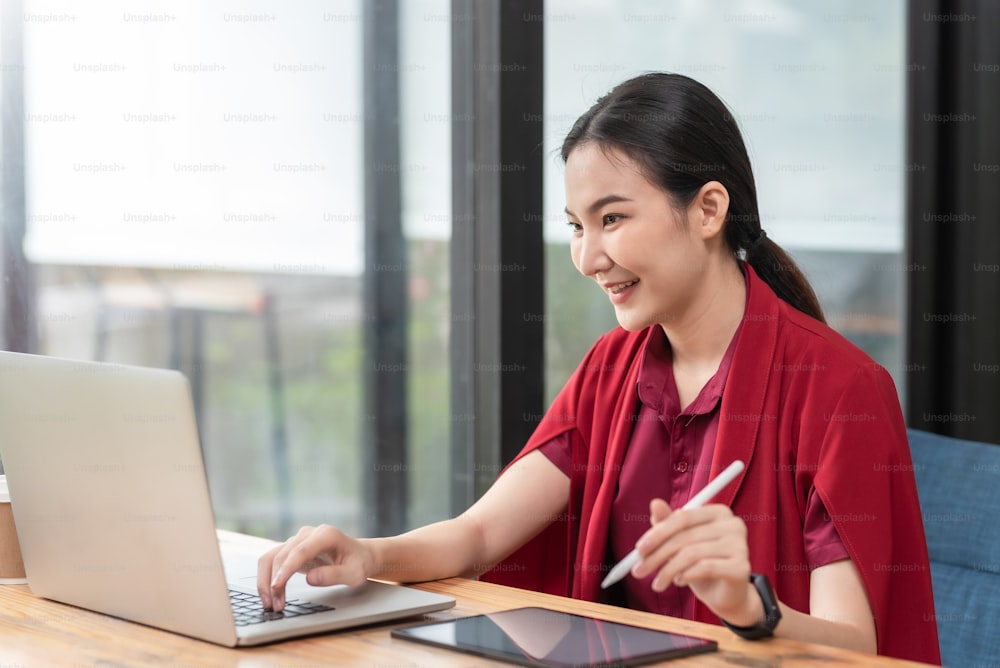 Porträt der lächelnden schönen asiatischen Geschäftsfrau sitzend genießen Sie die Idee mit Tablet und Laptop im Büro.