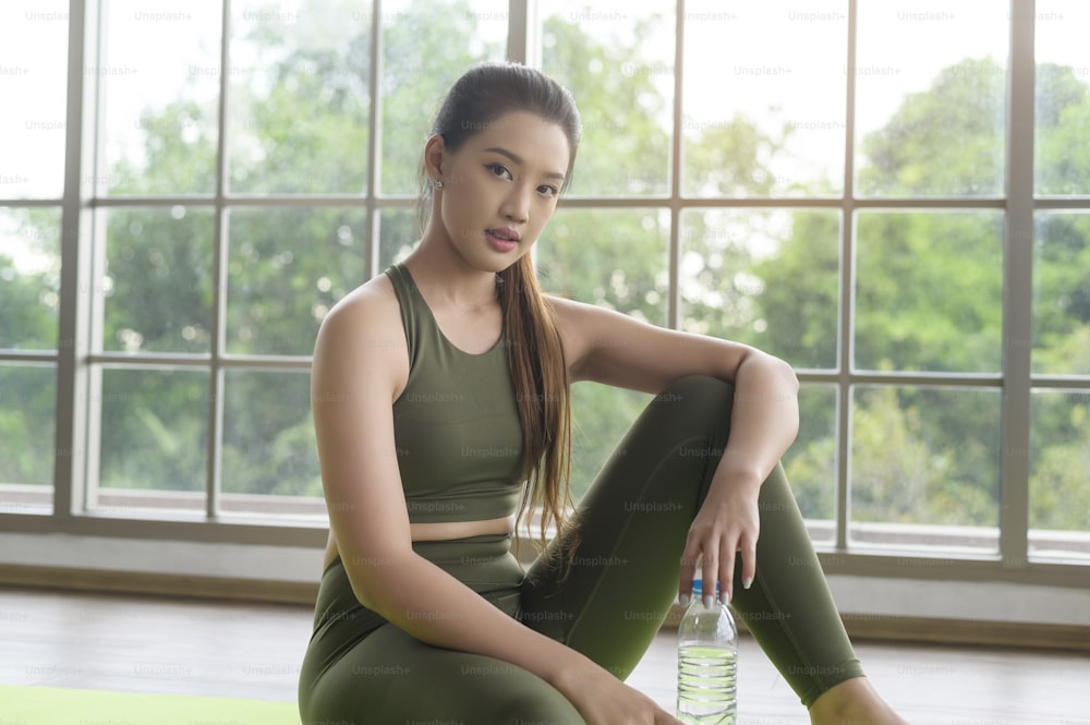 Young fitness woman in sportswear drinking water after exercising at home, Healthy and Lifestyles.