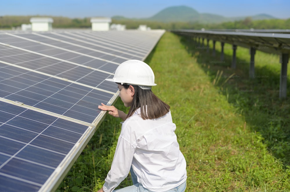 Eine Ingenieurin, die einen Helm in Photovoltaic Cell Farm oder Solar Panels Field trägt, umweltfreundliche und saubere Energie.