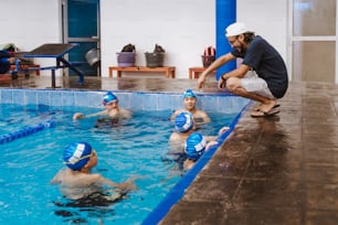 Latin swimming man trainer talking some advices to teenagers swimmers students at the pool in Mexico Latin America