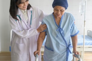 Médico que ayuda a la mujer paciente con cáncer que usa pañuelo en la cabeza con andador en el hospital, atención médica y concepto médico
