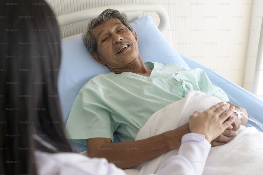 Doctor holding senior patient's hand in hospital, health care and medical concept
