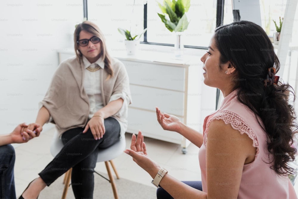 Hispanic young woman psychologist with couple patient in therapy talking about mental problems while doctor is listening and making notes in Mexico Latin America