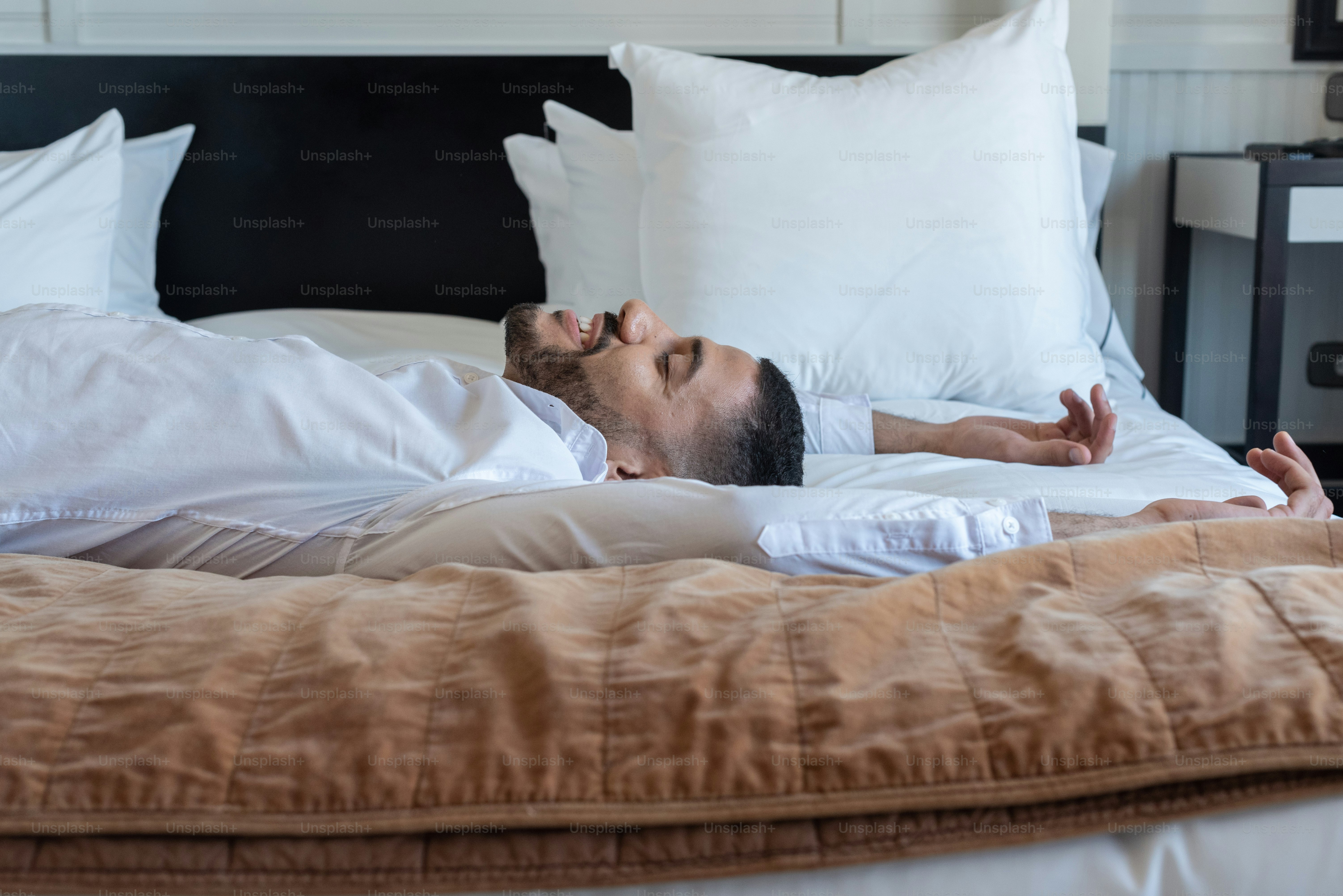 Young happy businessman lying on the hotel bed.