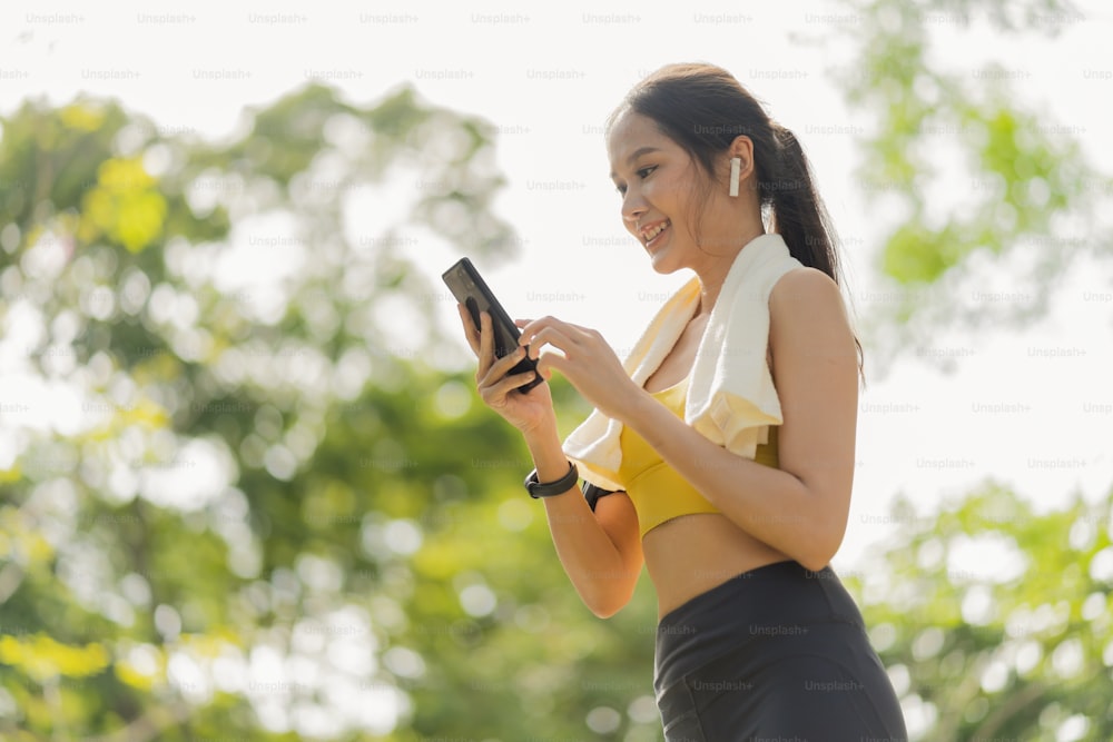スポーツアクティブアジアの女性のスポーツクロスは、スマートフォンの再生をセットアップし、ランニングルーチンのワークアウトの朝の健康的なライフスタイルの準備をし、笑顔のスポーツウーマンは彼女のアプリケーションマップでランニングルートを設定します