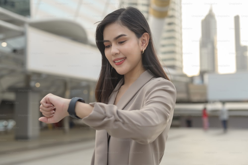 L'imprenditrice sta usando l'orologio intelligente nella città moderna, nella tecnologia aziendale, nel concetto di stile di vita della città