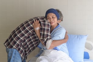 A Senior man visiting cancer patient woman wearing head scarf at hospital, health care and medical concept