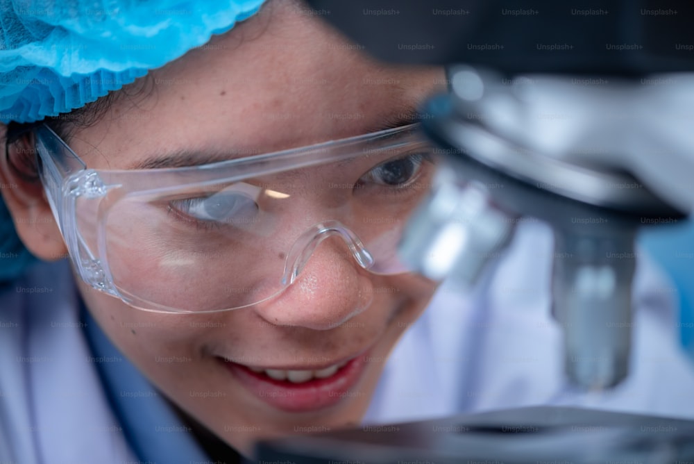 実験室で顕微鏡を覗く若い科学者。研究をしている若い科学者。