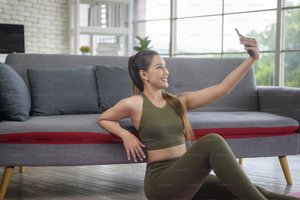 Young fitness woman in sportswear using smart phone while exercising at home, Healthy and Lifestyles.
