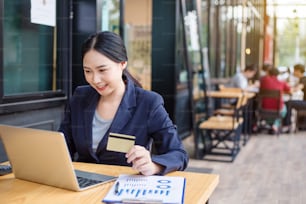 Young woman smiling. Business woman holding credit card and using laptop. Online shopping concept.