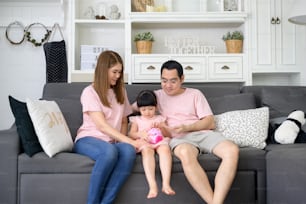 Una familia asiática está enseñando a su hija a ahorrar dinero con una alcancía, concepto de planificación financiera
