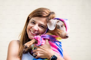 犬を抱くラテン系の女性は、どちらも同じような服装をしています。彼女はカメラを見ている。