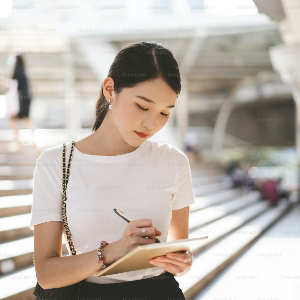 Tableta digital interactiva para mujeres asiáticas que trabajan en negocios para adultos jóvenes para corporativos con equipo a través de Internet.  Estilo de vida con tecnología moderna. Fondo de tamaño cuadrado.
