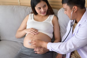 Un medico che tiene lo stetoscopio sta esaminando una donna incinta in ospedale, assistenza sanitaria e concetto di assistenza alla gravidanza