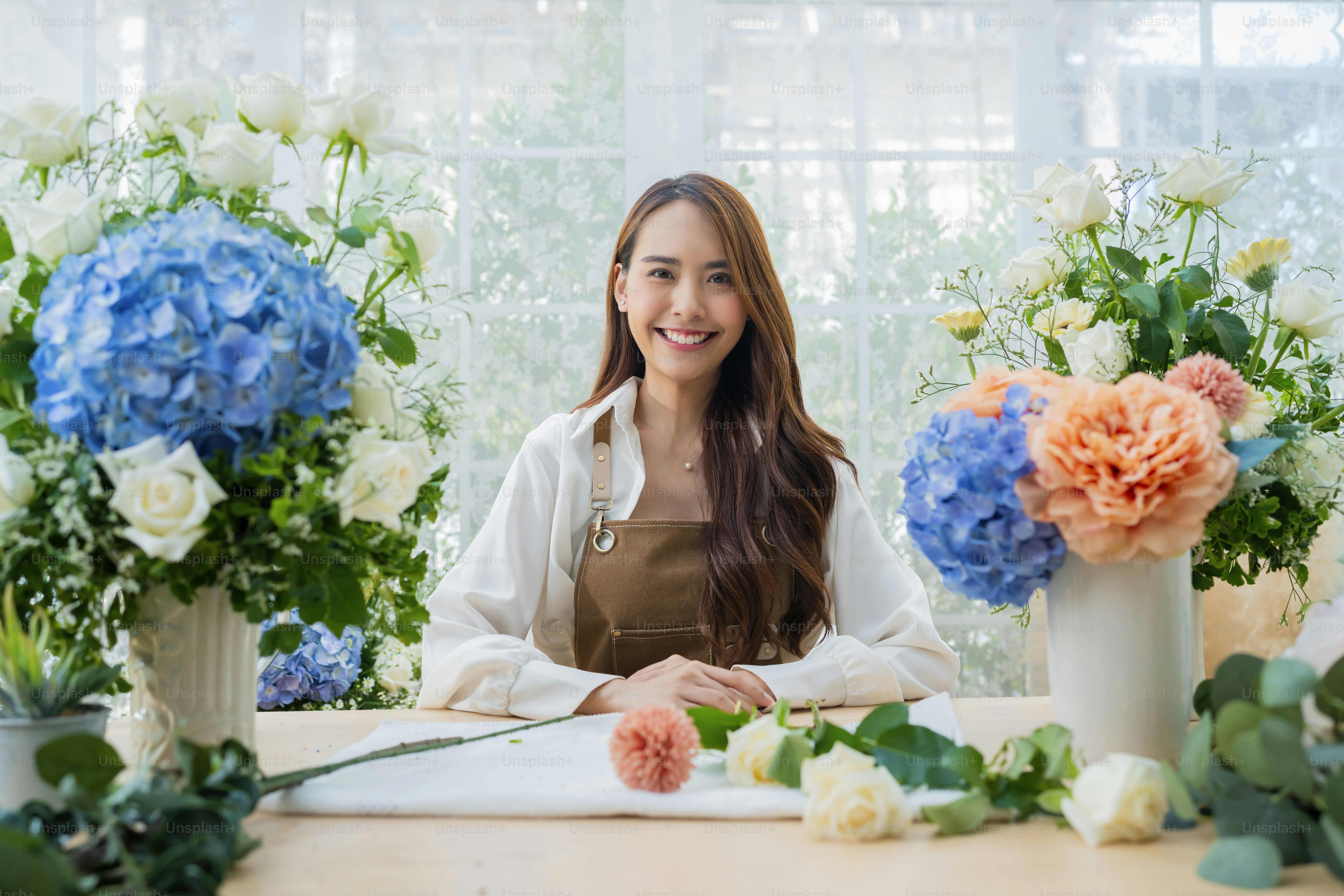 portrait Asia Female florist smile arranging flowers in floral shop. Flower design store. happiness smiling young lady making flower vase for customers, preparing flower work from home business