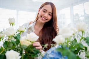 Kleinbetrieb. Asia Floristin Lächeln arrangiert Blumen im Blumenladen. Blumendesign-Laden. Glück lächelnde junge Dame, die Blumenvase für Kunden herstellt, Blumenarbeiten von zu Hause aus vorbereitet