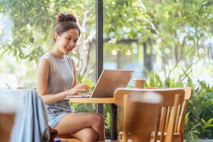 digital nomad millennial gen x lifestyle,asian female freelance casual working from cafe working anywhere work while vacation smiling hand type laptop cheerful positive thinking work remotely in cafe
