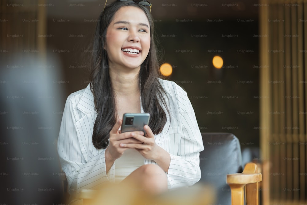 Belle jeune femme asiatique utiliser un smartphone dans un café recevoir un e-mail texte bonnes nouvelles PME à propos de son client accepter le contrat traitant un nouveau projet proporsal Jeune millennial asiatique femme gesticuler café