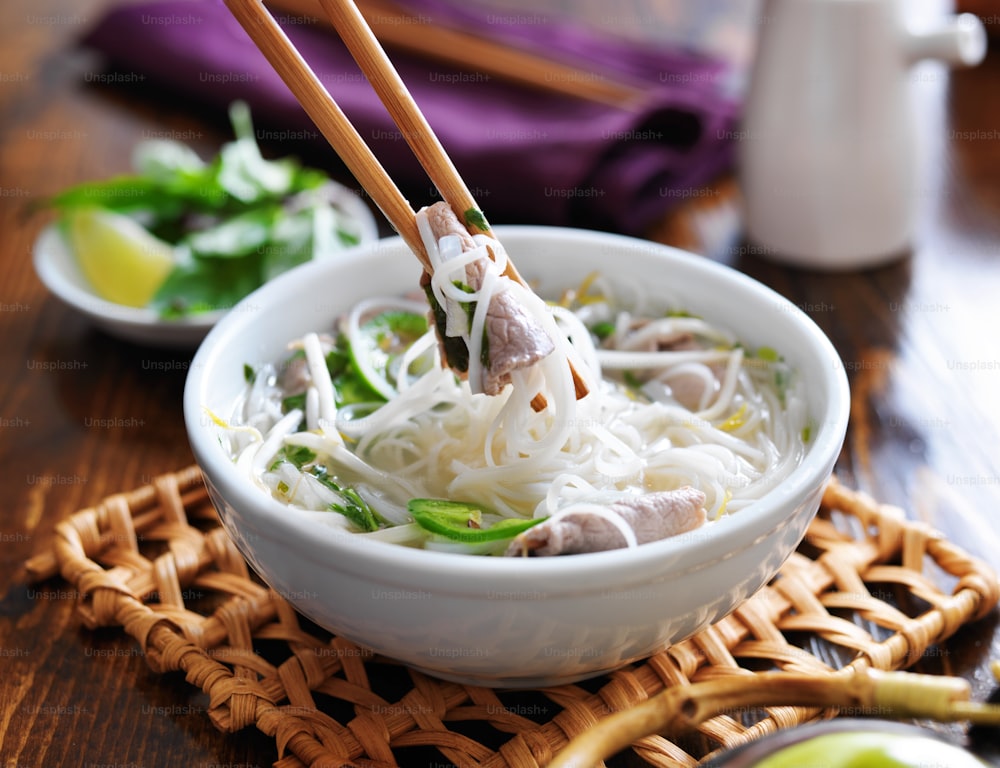 eating a bowl of pho with noodles and beef with chopsticks