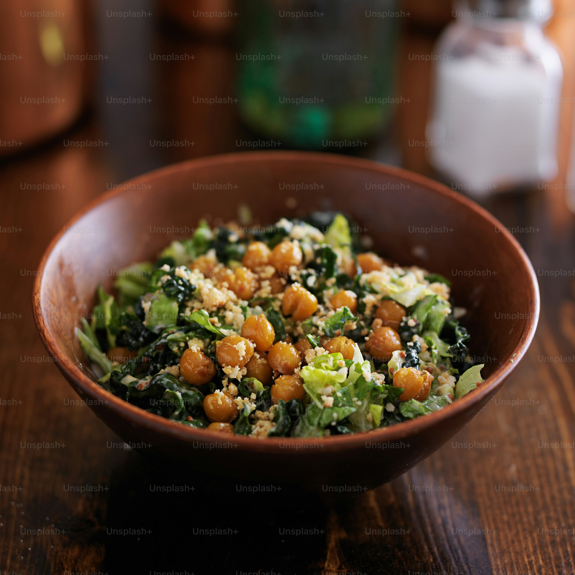 vegan caesar salad in wooden bowl on wooden table with dark lighting