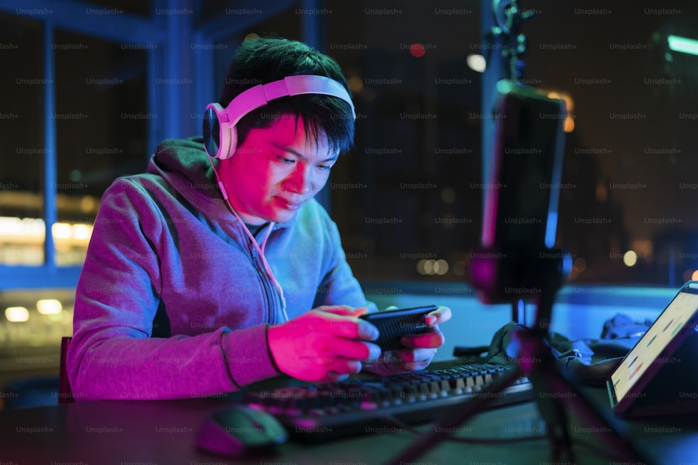 asian male esports gamer playing online sport leagues multiplayer game via smartphone with exited and cheerful emotion,asian male wear headset playing smartphone game online together with friends