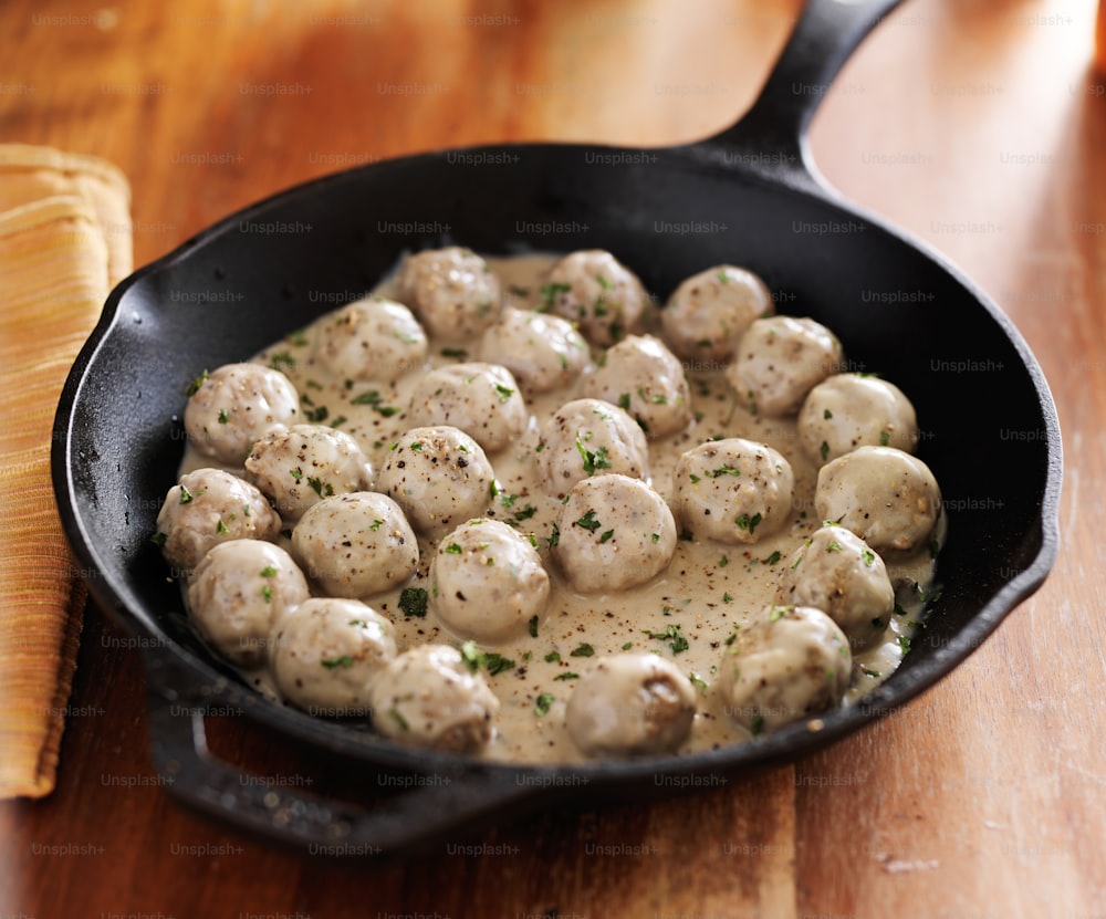 swedish meatballs in iron skillet on top of wooden table cooling down