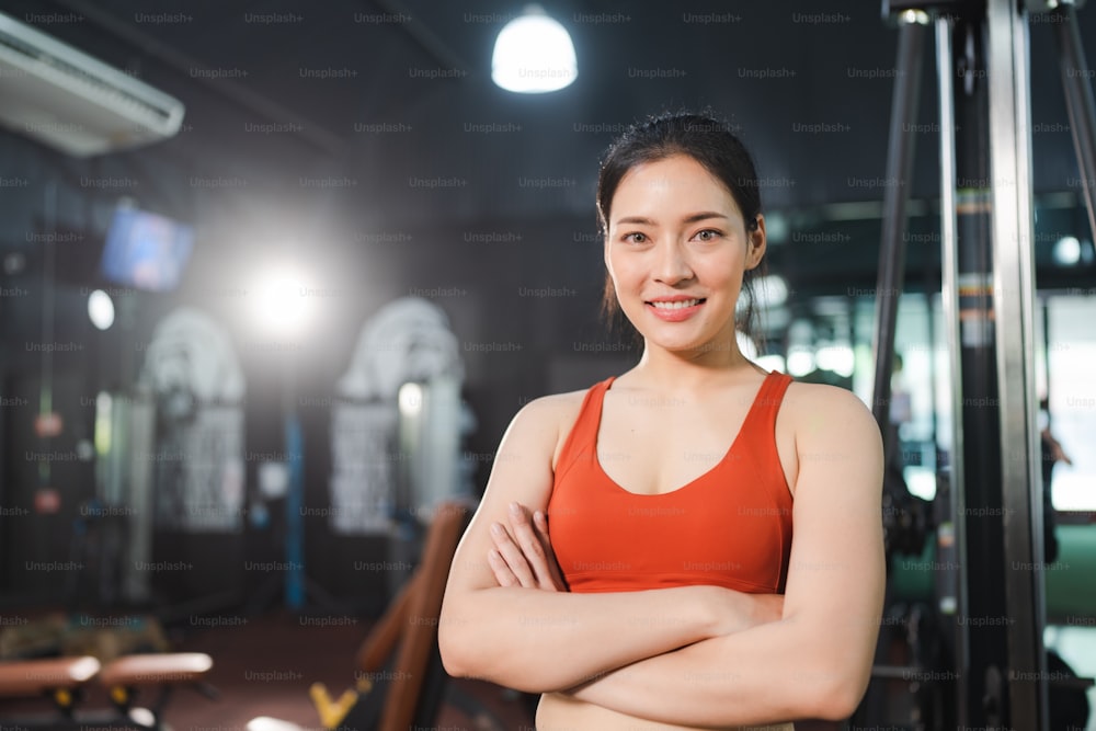 young Asian woman person exercise in fitness gym for building a beautiful slim body, healthy training of athletic female in sport lifestyle, attractive girl doing weight active wellness in happy