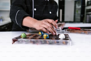 mano de una chef pastelera latina vestida de uniforme negro en el proceso de preparación de deliciosos chocolates dulces en la cocina de México América Latina