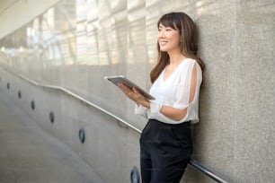 belle jeune femme d’affaires asiatique utilise une tablette dans une ville moderne