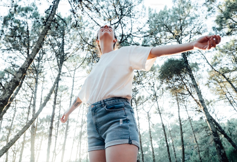 a woman standing in a forest with her arms outstretched