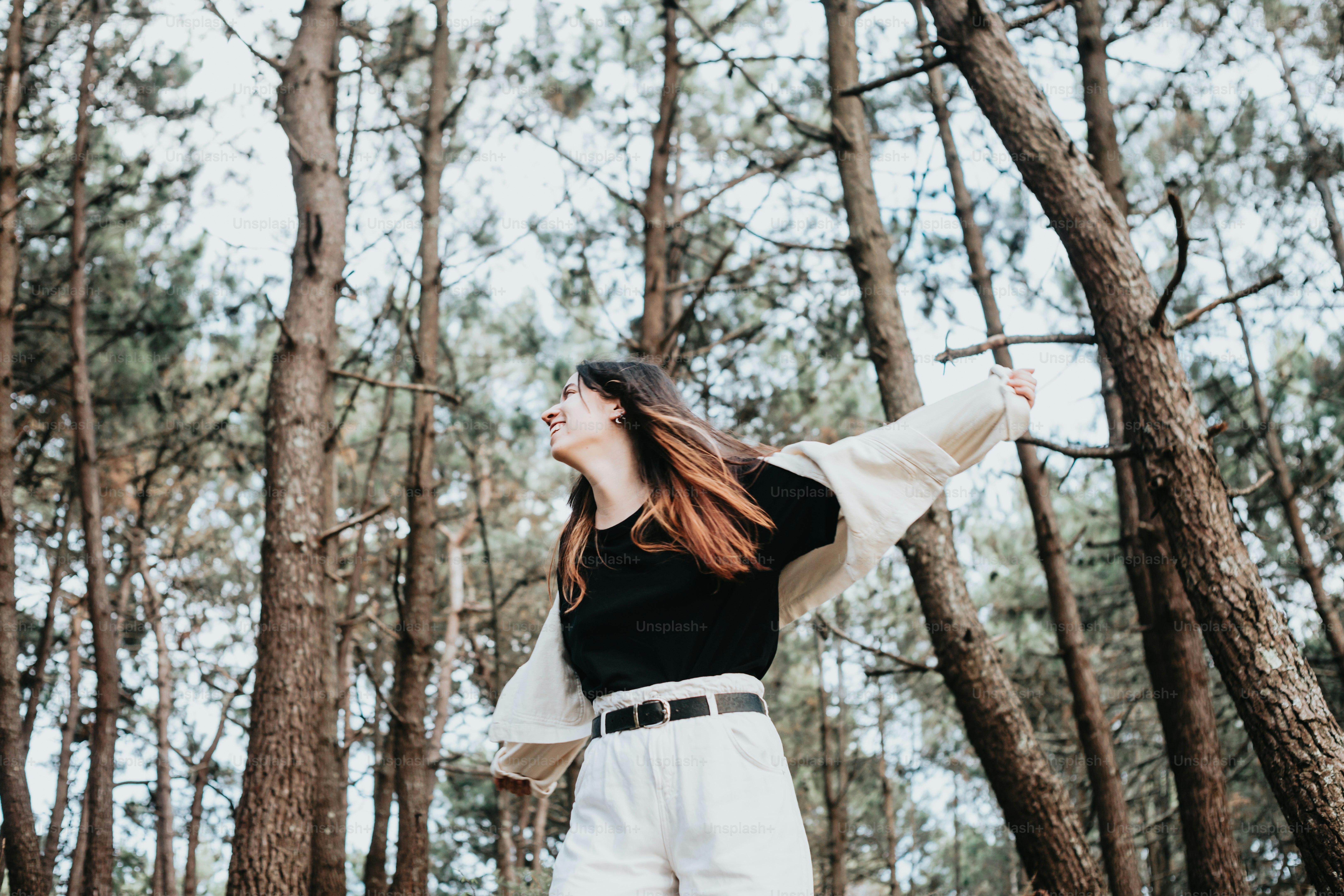 a woman standing in the middle of a forest