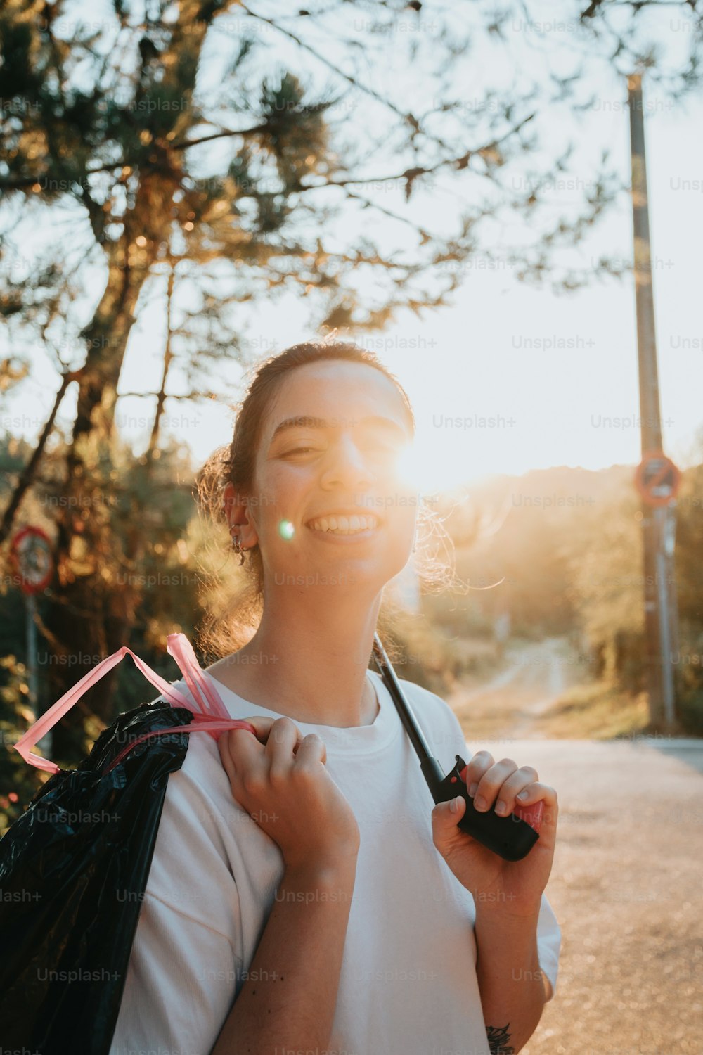 a woman smiles while holding a black bag