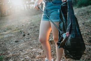 a woman holding a black bag in a forest