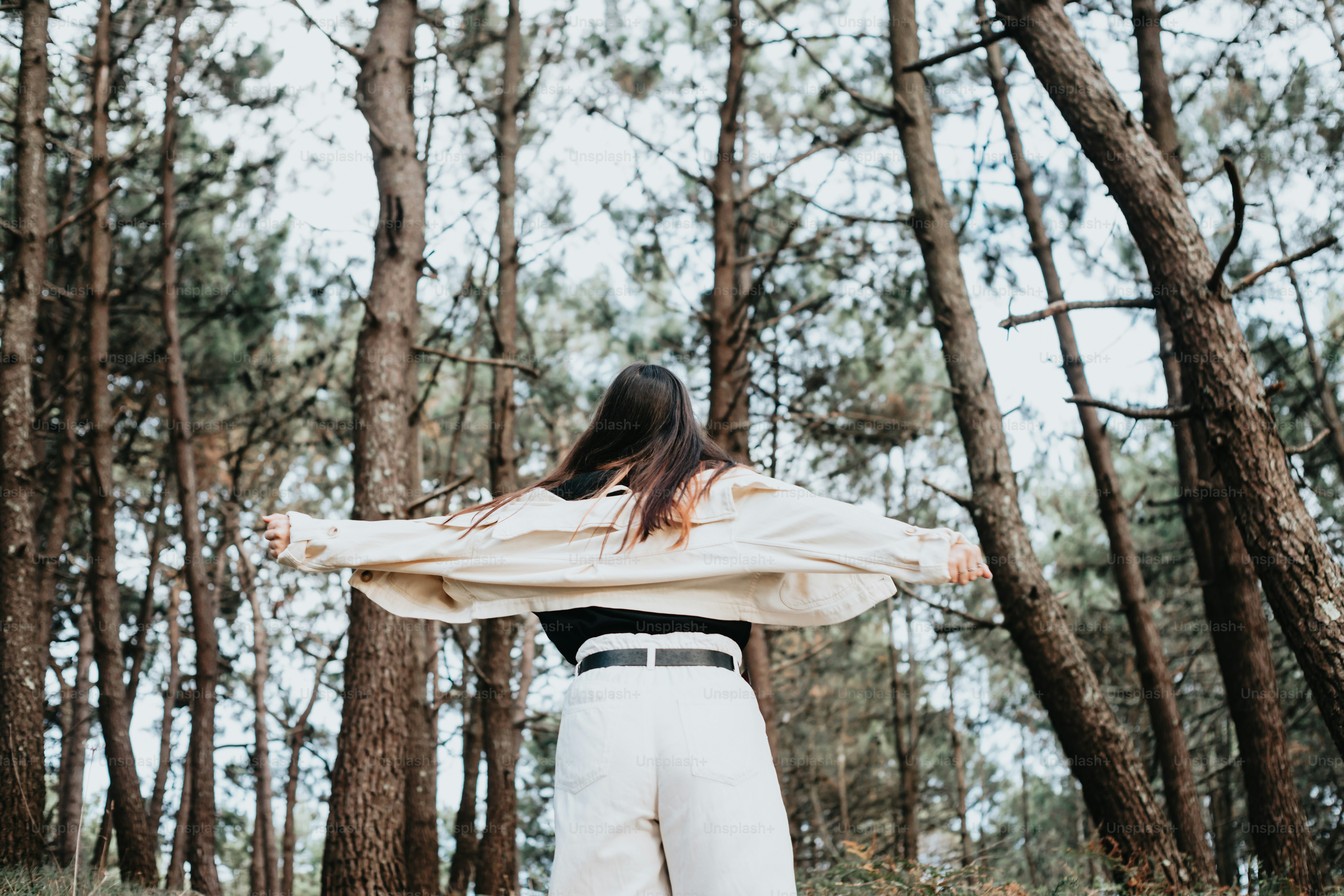 a woman standing in the middle of a forest