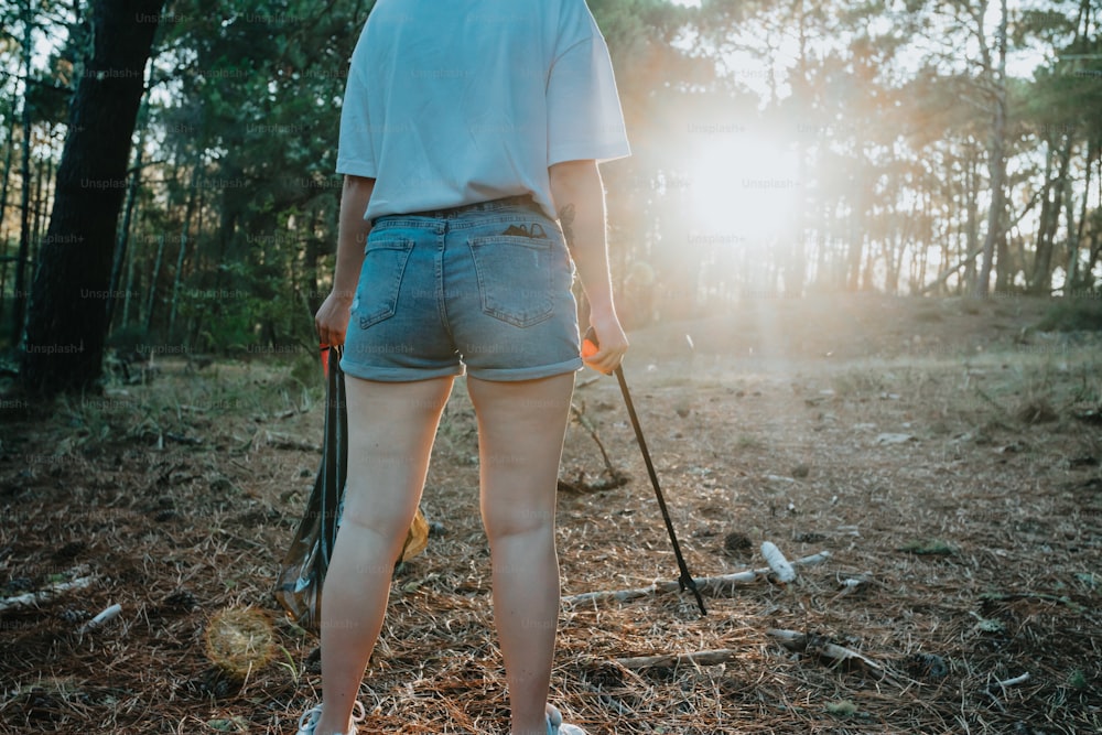 Una mujer caminando por un bosque sosteniendo un palo