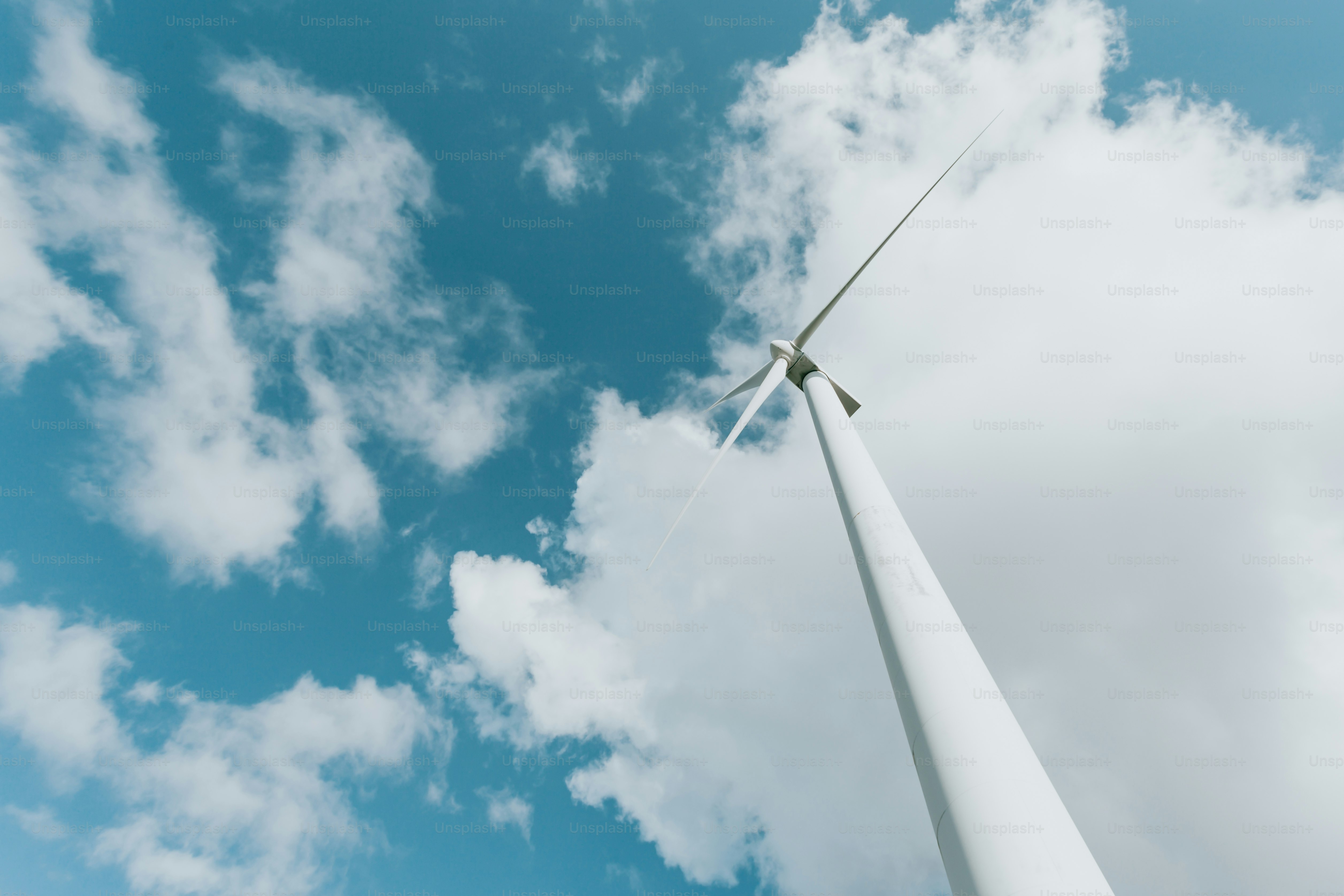 a wind turbine in the middle of a cloudy blue sky