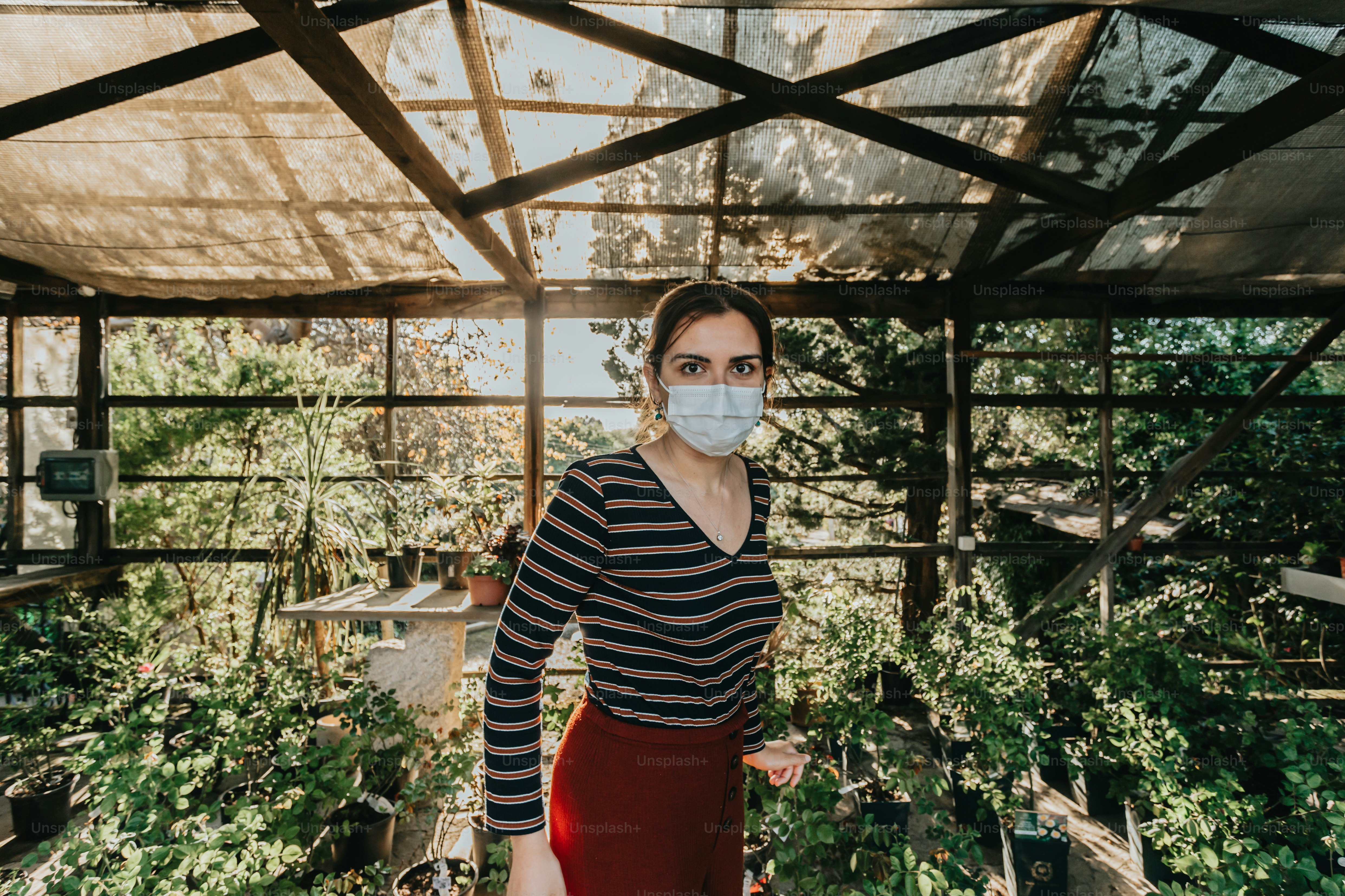 a woman wearing a face mask in a greenhouse