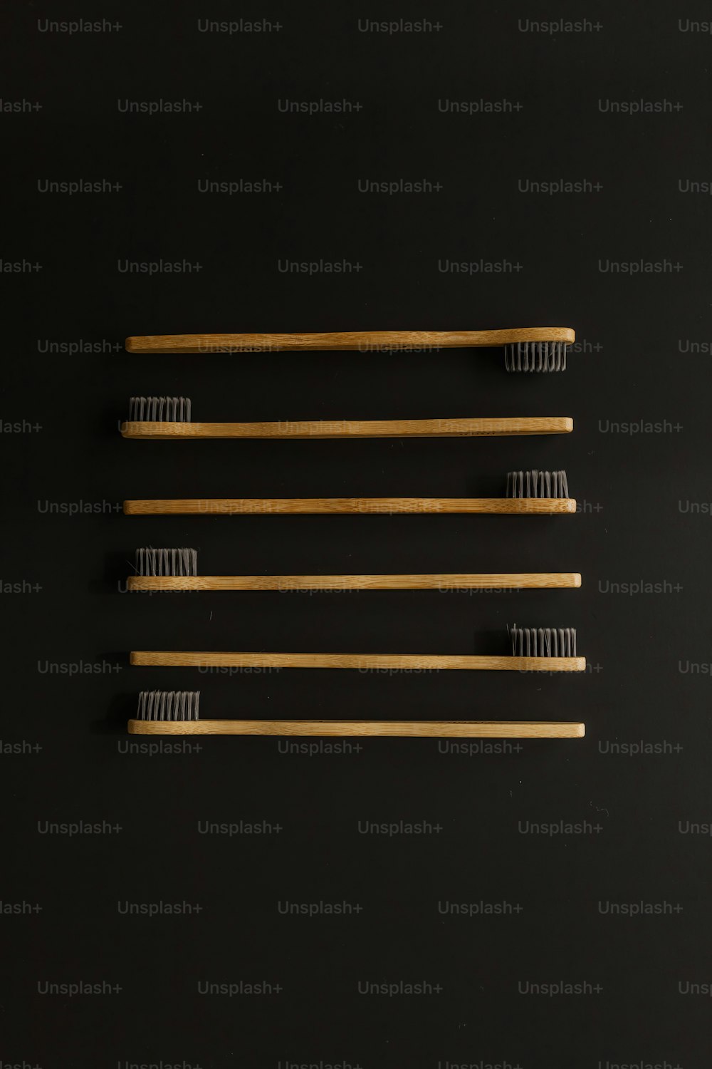 Quattro spazzolini da denti allineati su una superficie nera