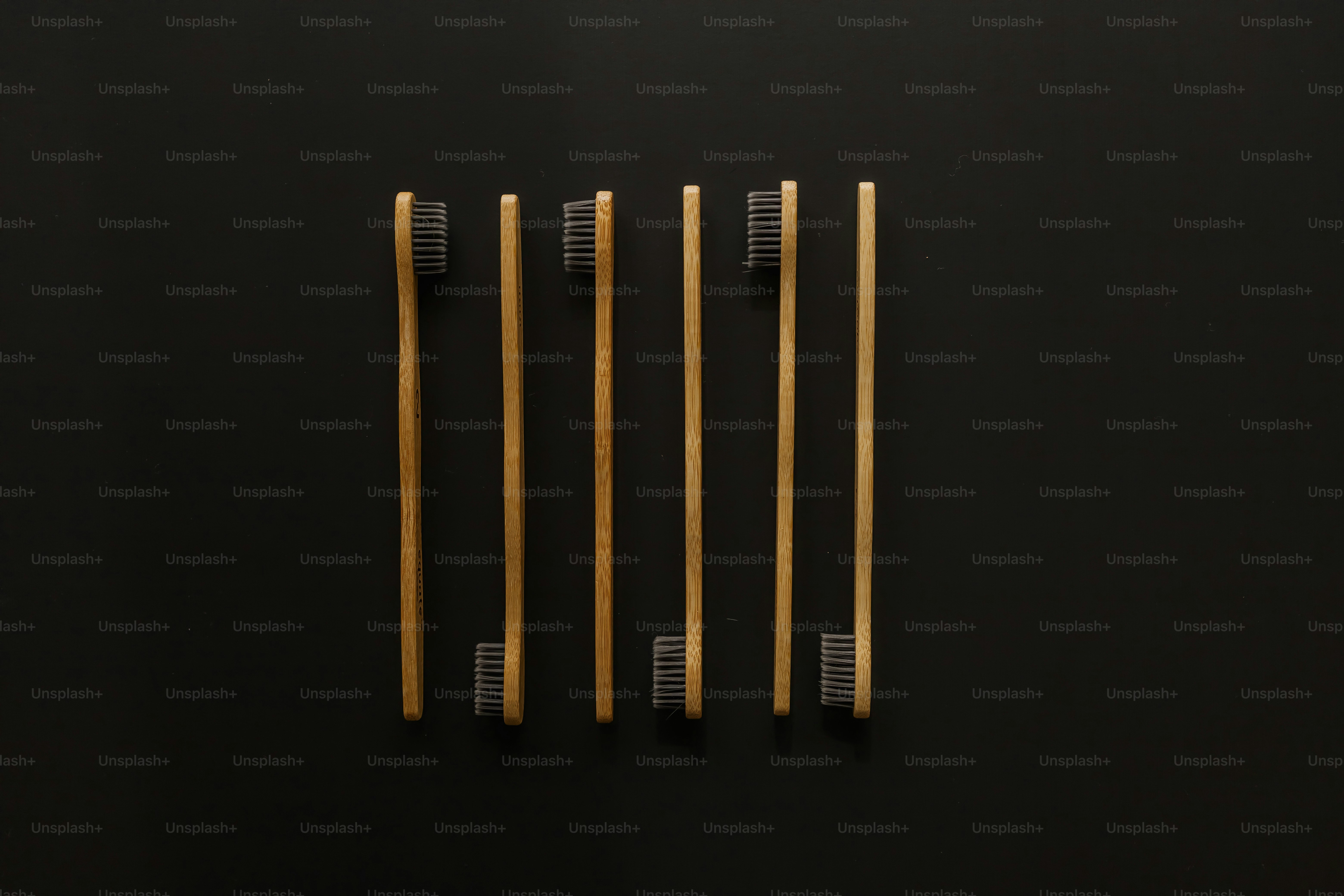 three wooden toothbrushes on a black surface