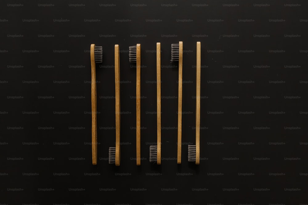 três escovas de dentes de madeira em uma superfície preta