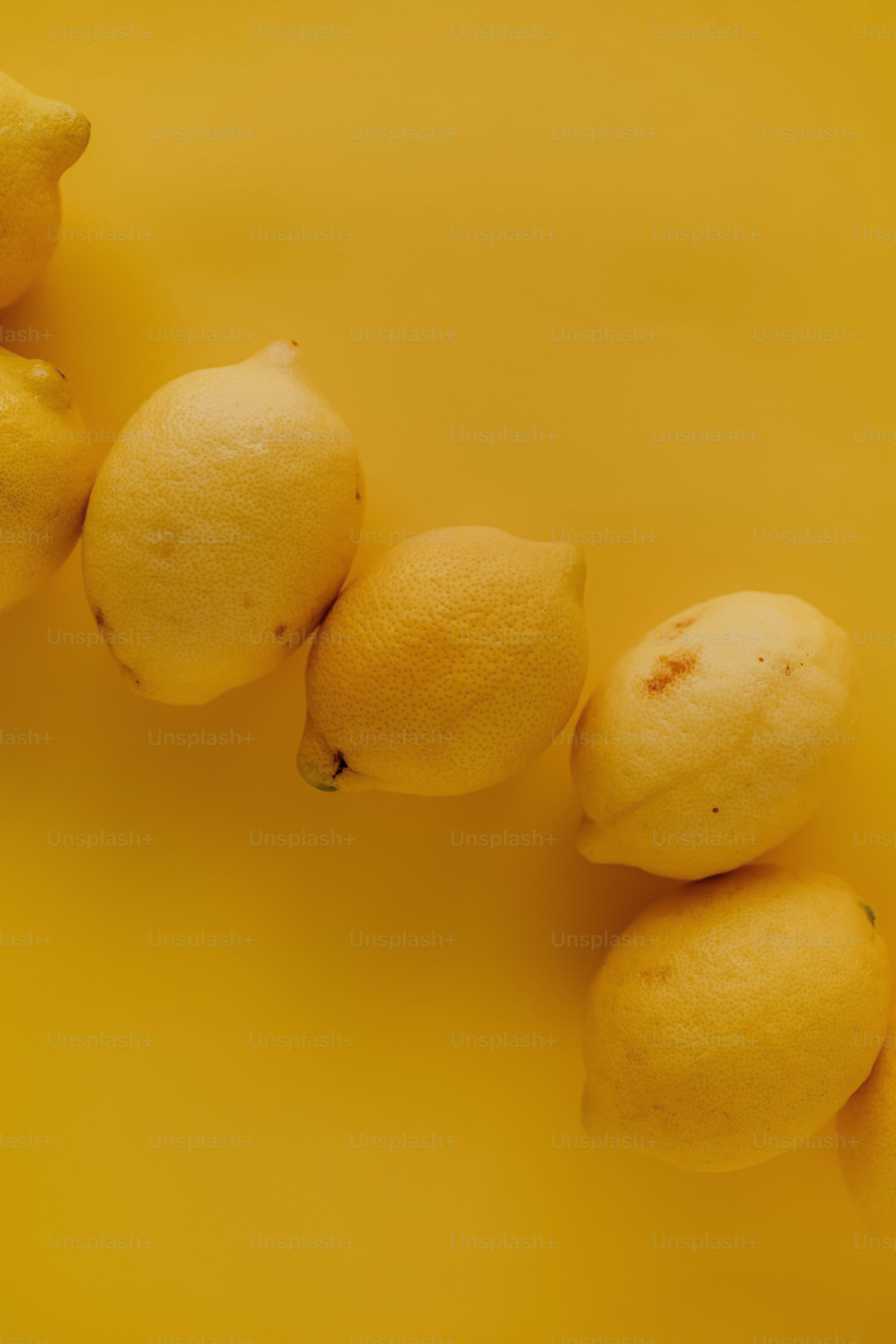 a group of lemons sitting on top of a yellow surface