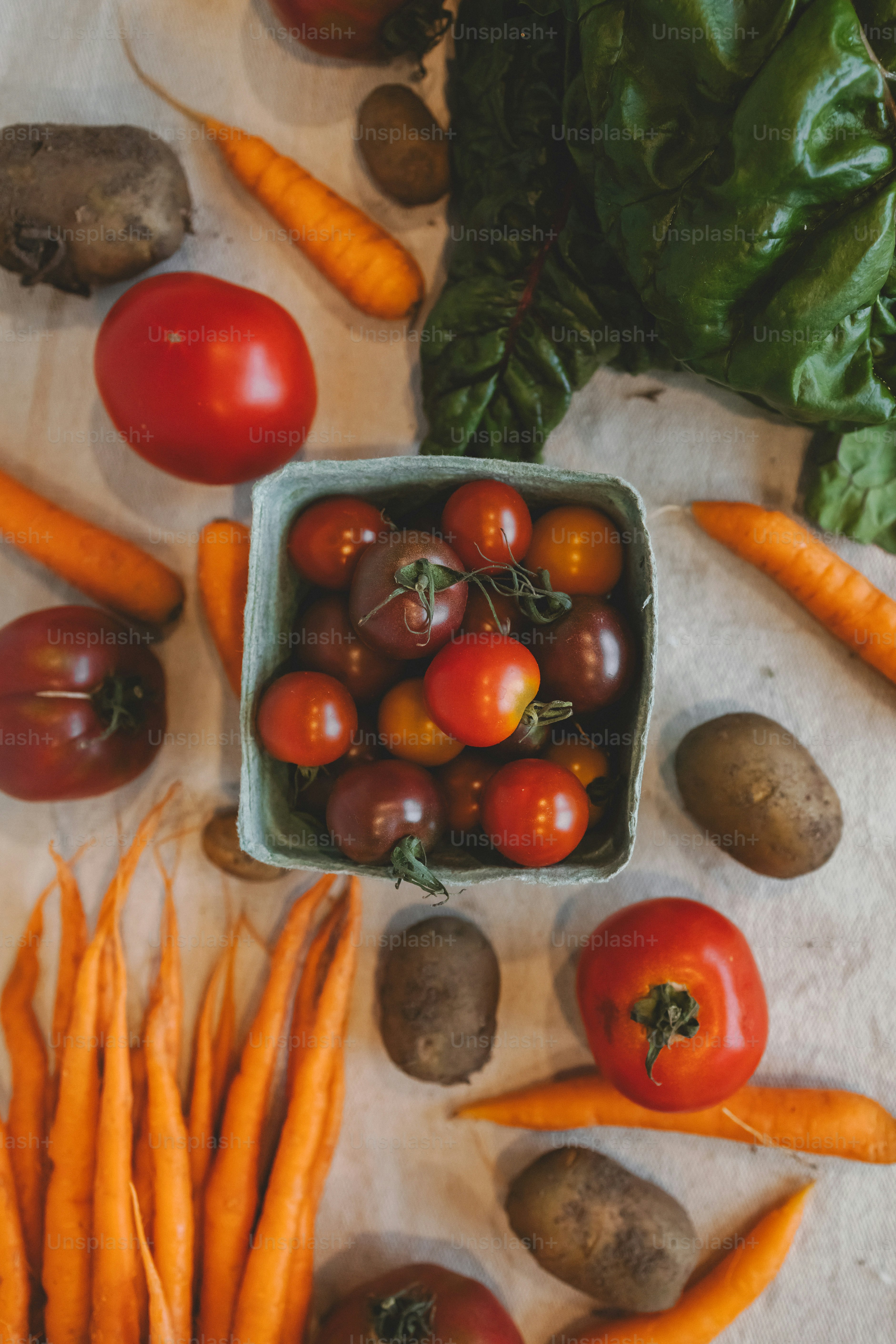 a bowl of tomatoes, carrots, and potatoes on a table