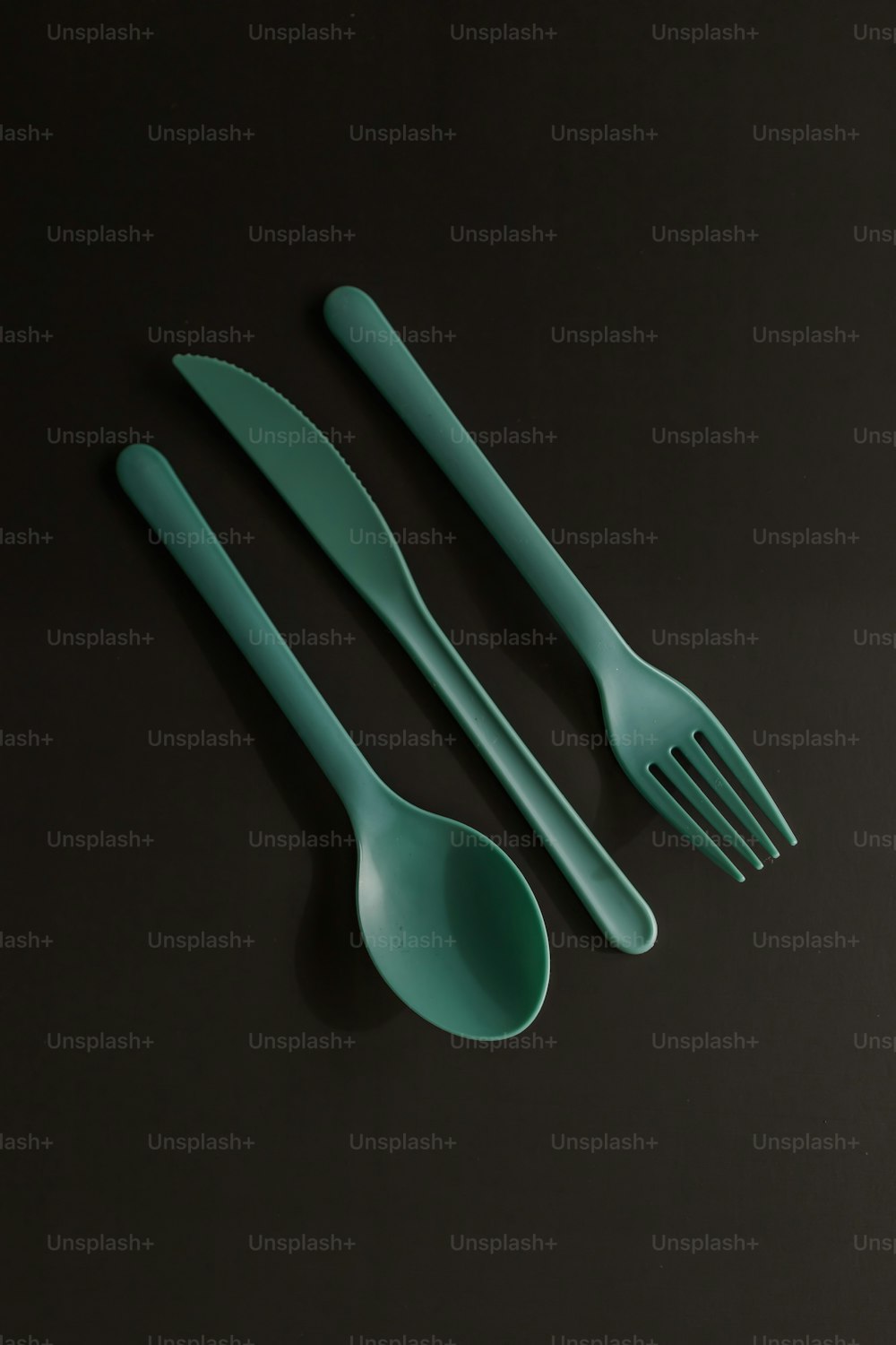 a set of green plastic utensils on a black surface