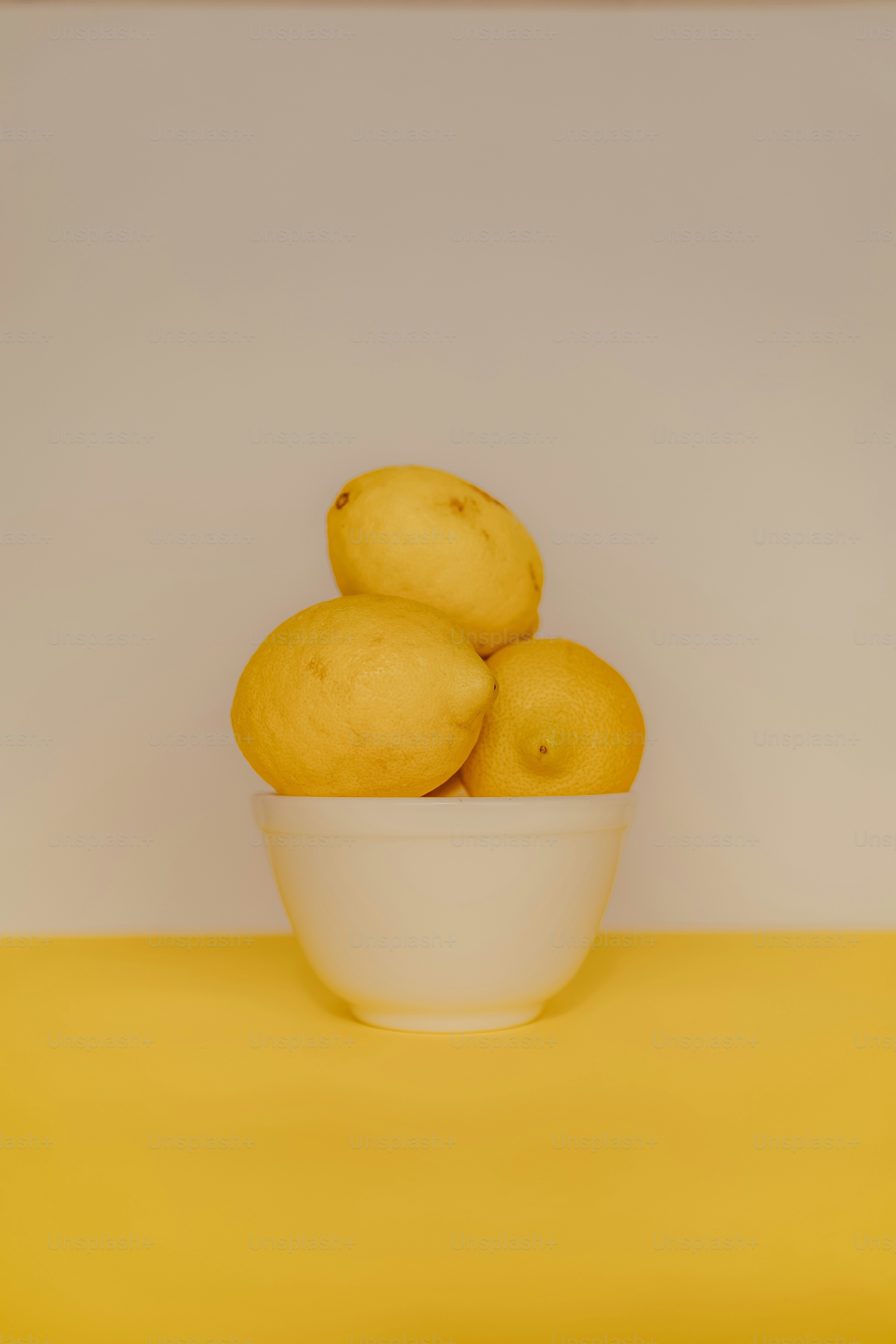 a bowl of lemons on a yellow table