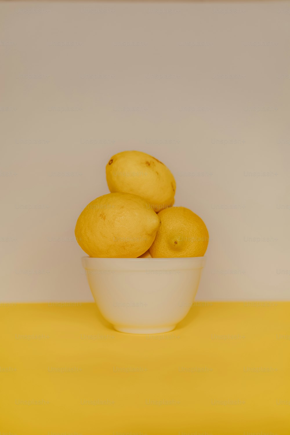 un tazón de limones sobre una mesa amarilla
