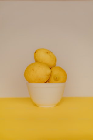 a bowl of lemons on a yellow table