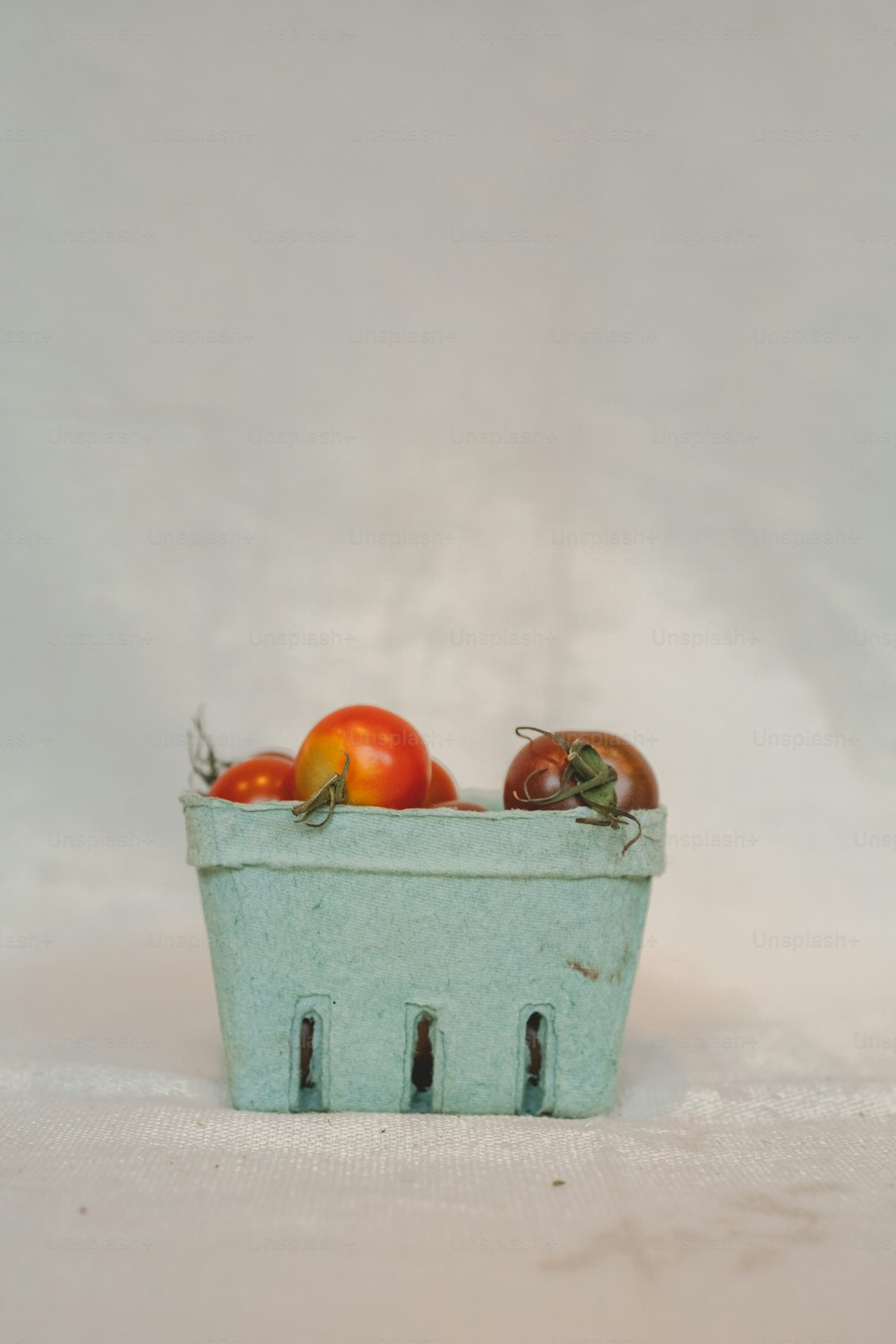 a blue basket filled with lots of tomatoes